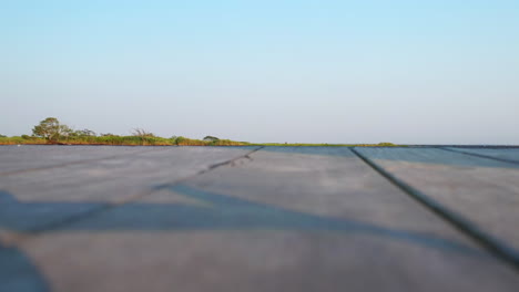 low-aerial-drone-shot-steadily-hovering-over-the-waters-at-East-Islip-Marina---Park-with-the-marsh-area-in-view-then-land-with-the-shadow-of-the-drone---props-winding-down-at-sunset