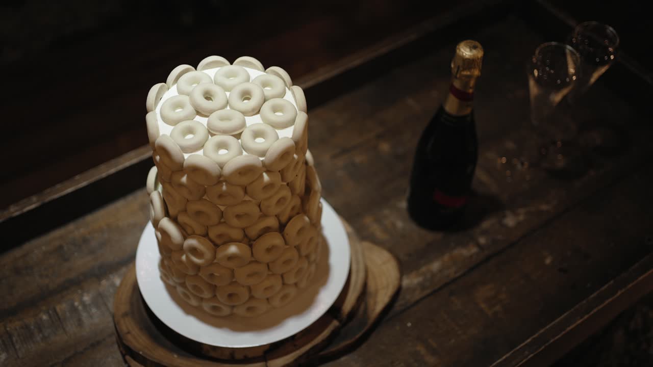 Elegant wedding cake adorned with white cookies on a rustic wooden table at night