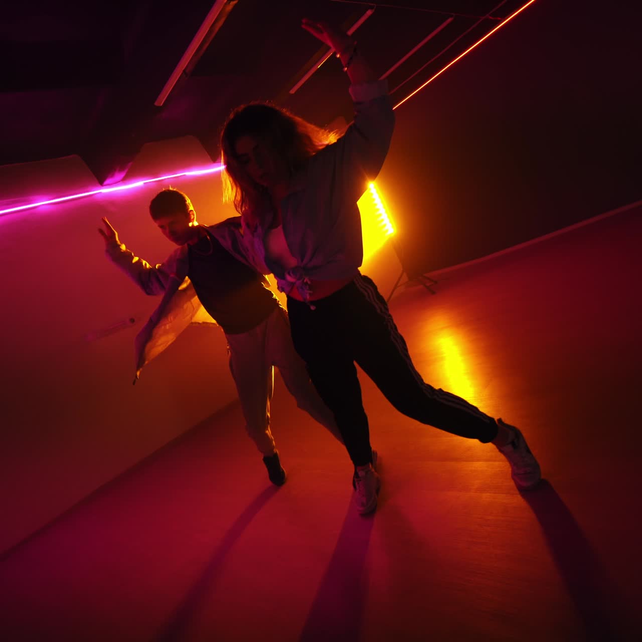 Pair dancing of hip hop. Young diverse dancers performing modern dance style in the studio with pink light