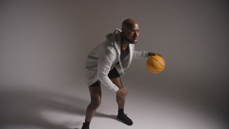 toma de estudio de un jugador de baloncesto masculino dribbling y lanzando la pelota contra un fondo oscuro 1