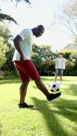vertical video: friends playing soccer in sunny backyard, enjoying outdoor activity together