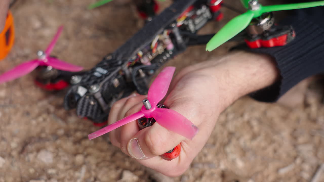 Persona che attacca un'elica rosa al motore di un drone FPV