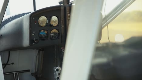 small plane cockpit shot whilst panning camera movement looking threw from the outside wing and shell of the white plane during a sunny day