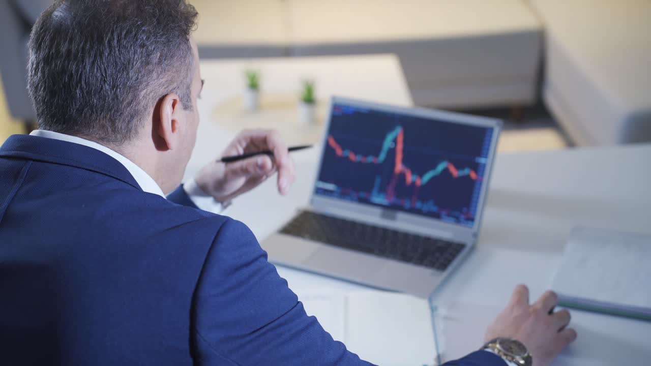 comerciante mirando y analizando gráficos del mercado de valores en su computadora portátil.