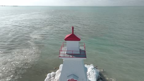 Red-lighthouse-at-Southampton-pier-with-calm-blue-waters,-daytime,-clear-sky,-aerial-view