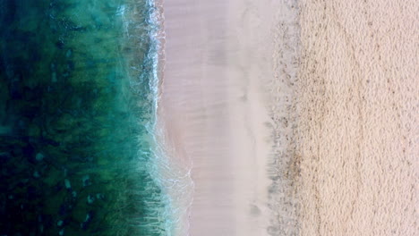 Toma-Aérea-De-Una-Playa-De-Arena-Vacía-Con-Suaves-Olas-Golpeando-La-Costa