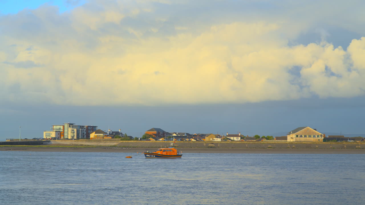 폭풍우 가 불고 있는 하늘 이 지나가고 무지개 가 지평선 에 비 줄기 들 이 나타나며,  ⁇ 어 있는 구명 보트 가 해가 지는 동안 강 입구 에 들어오는 조류 와 함께 움직인다