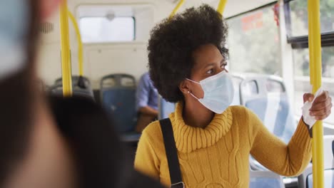 mujer de negocios afroamericana con máscara de cara de pie en el autobús