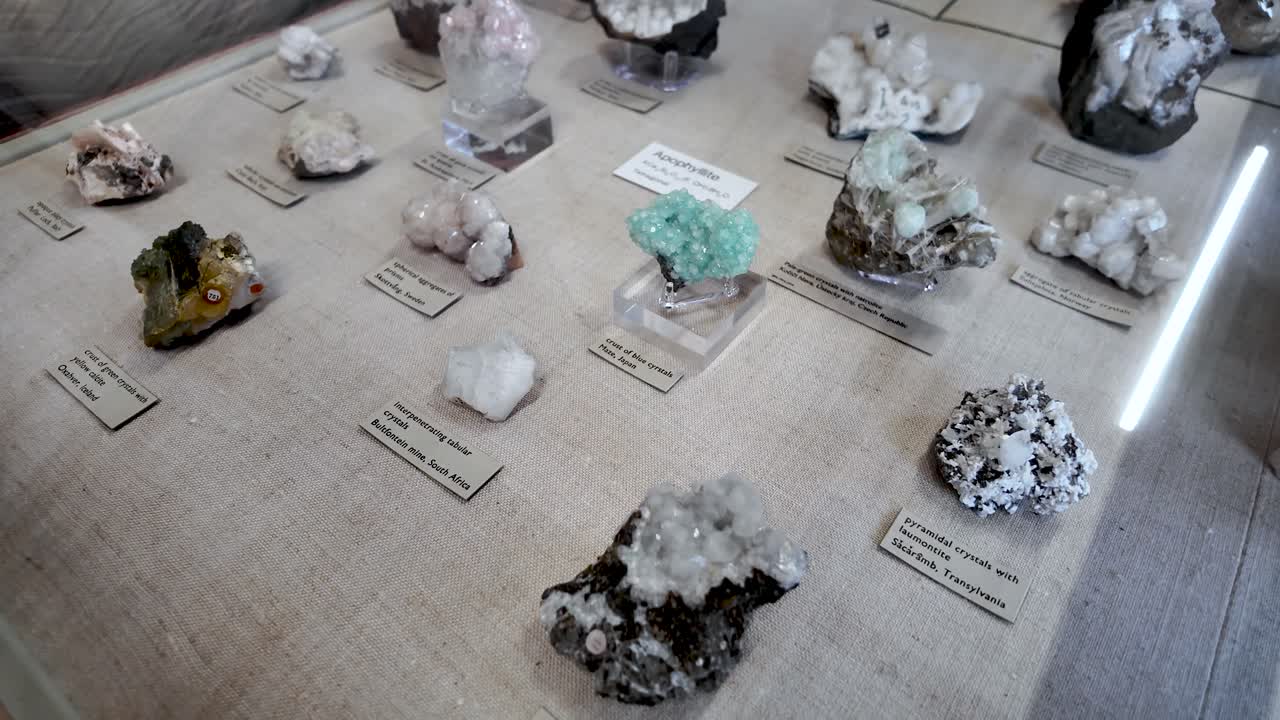 Forskellige geologiske klippeformationer og naturlige krystaller arrangeret inde i et glasskab