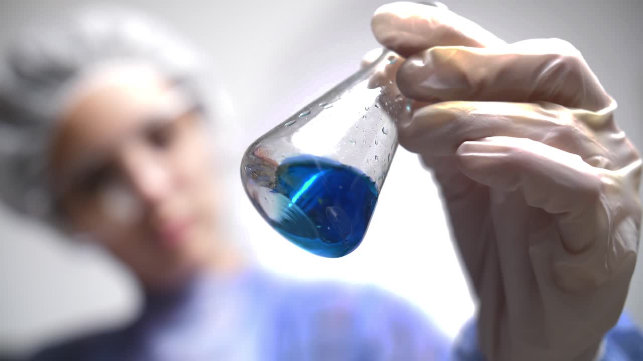 Scientist in Lab Coat Swirling Blue Liquid in Conical Flask