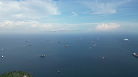 a wide drone shot during daytime panning from a group of vessels waiting in the pacific ocean to the panama canal