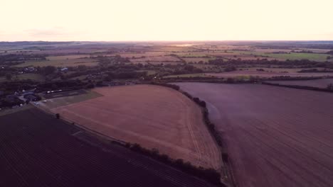 Langsam-Hinunter-Zu-Einem-Abgeernteten-Feld,-Während-Sie-Auf-Einen-Sommersonnenuntergang-Blicken