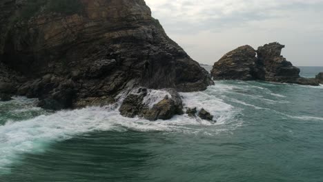 aerial shot of a wave crashing in a rock formation in la ventanilla, oaxaca