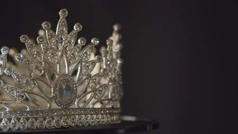 beauty pageant, bride's or queen's crown on a turning display as in a museum, illuminated with black background