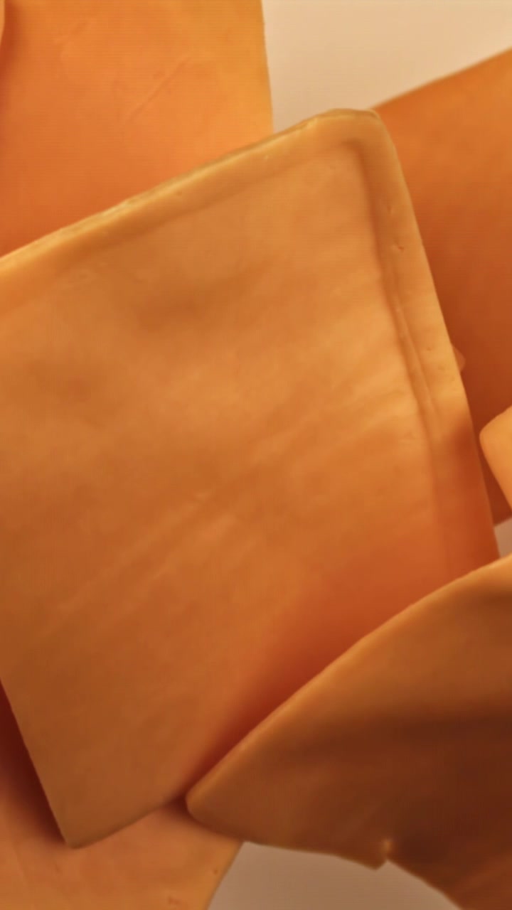 Primo piano di fette di formaggio arancione che si sciolgono
