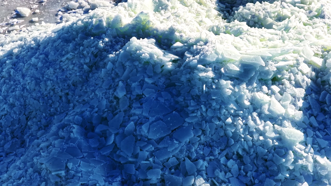 Ice floe pile in aerial view on sunny winter day on shore of frozen sea