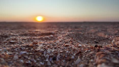 Erleben-Sie-Einen-Atemberaubenden-Sonnenuntergang,-Der-Das-Ruhige-Wasser-Des-Asowschen-Meeres-Erhellt,-Mit-Einem-Strand-Voller-Muscheln