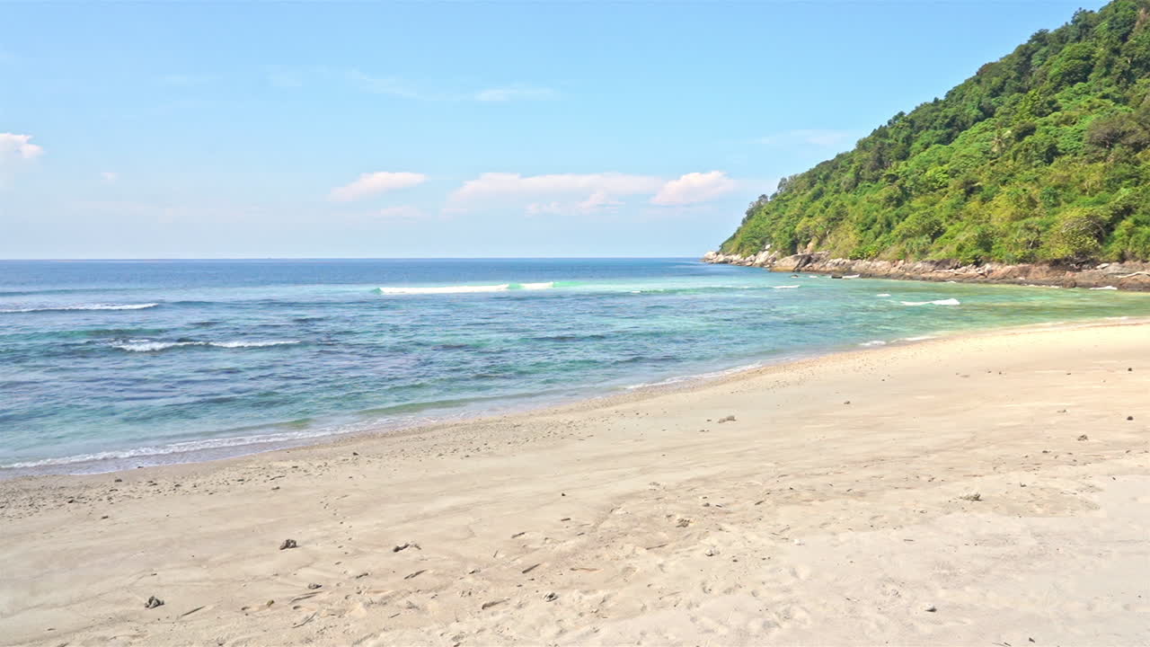 蓝色海浪拍打着热带空旷的海滩。