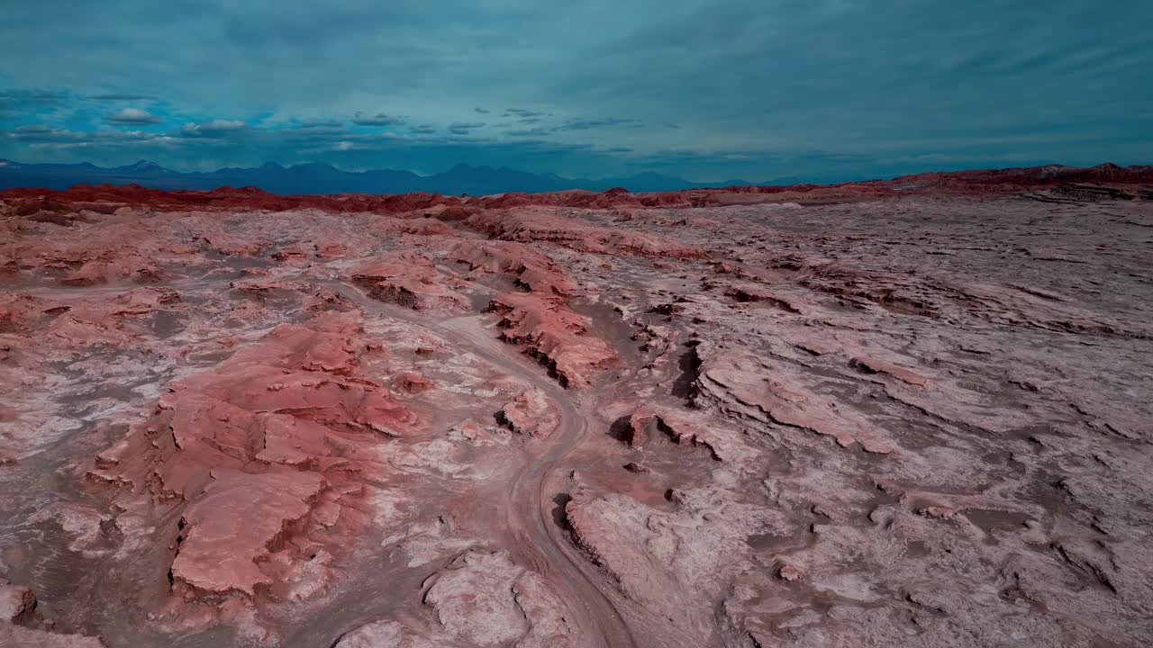 Descending drone aerial of Valle de la Luna's Mars-like terrain, San Pedro de Atacama, Chile with red layered rock formations at twilight
