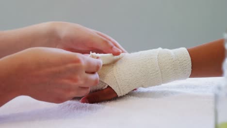 Physiotherapist-putting-bandage-on-injured-hand-of-patient-4k