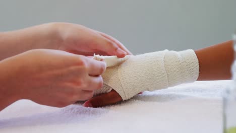 physiotherapist putting bandage on injured hand of patient 4k