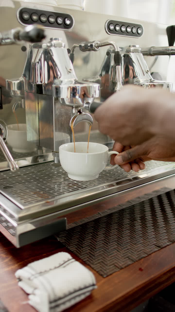 Vertical video: Making espresso, barista using coffee machine in cafe, preparing fresh coffee