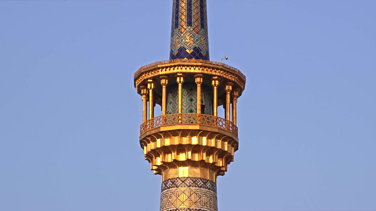 Gylden minaret af en traditionel moské mod en klar blå himmel
