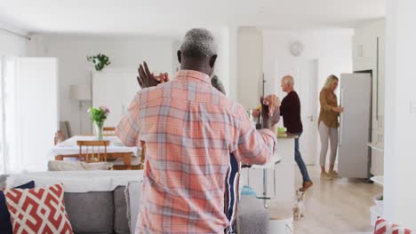 afrikanisch-amerikanisches älteres paar tanzt in einem wohnzimmer mit einem älteren kaukasischen paar im hintergrund