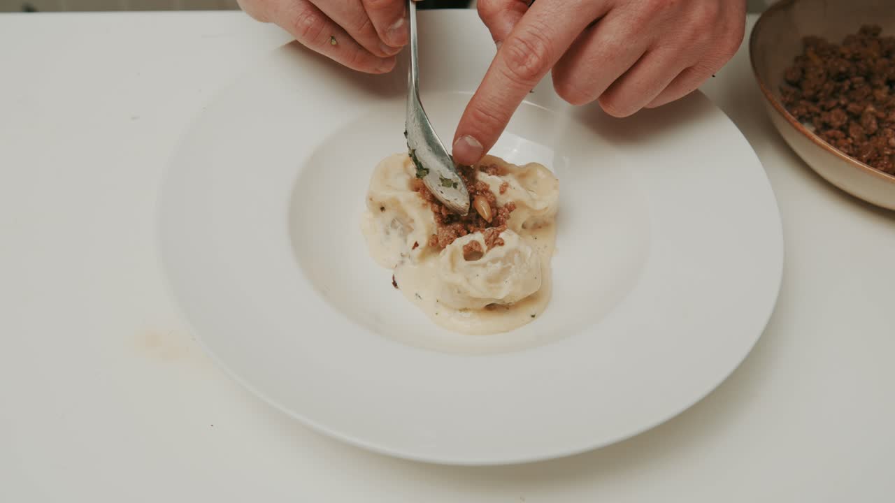 Plating dumplings in yogurt cream dish, adding pine tree seeds