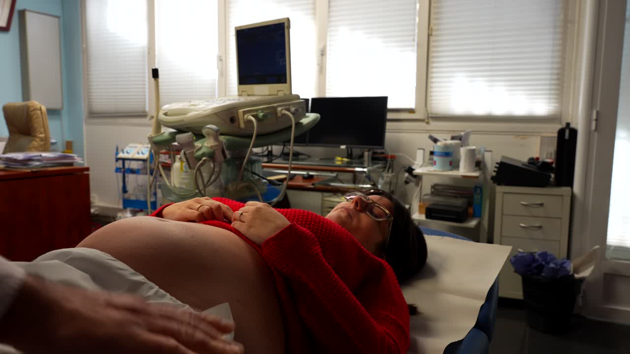 Medico che prepara una paziente incinta per un'ecografia del bambino.