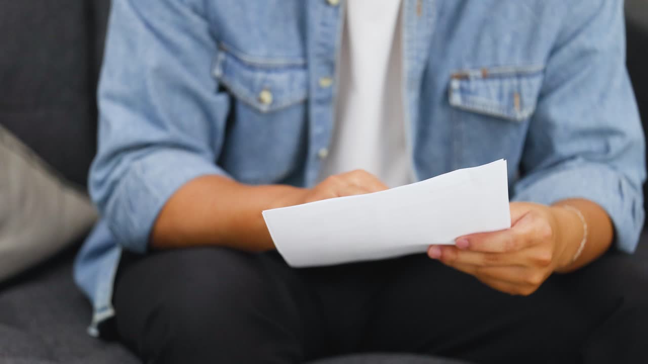 Una persona con una giacca di jeans seduta che esamina attentamente documenti e contratti su carta bianca