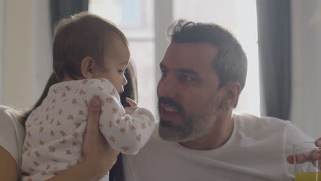 happy married couple playing with their little daughter in bed on sunday morning