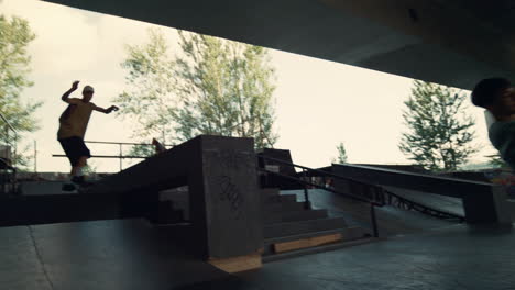 teenager riders practicing together on scooter and skate board city skatepark.