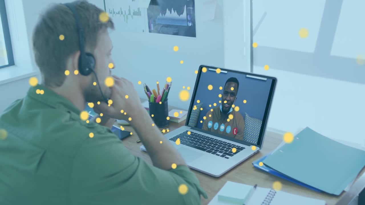 Animation of bitcoin icons over caucasian man using phone headset and laptop