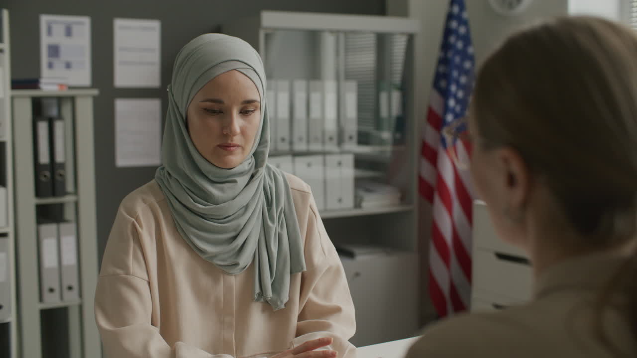 Young Woman in Hijab Talking to Consular Officer during Visa Interview