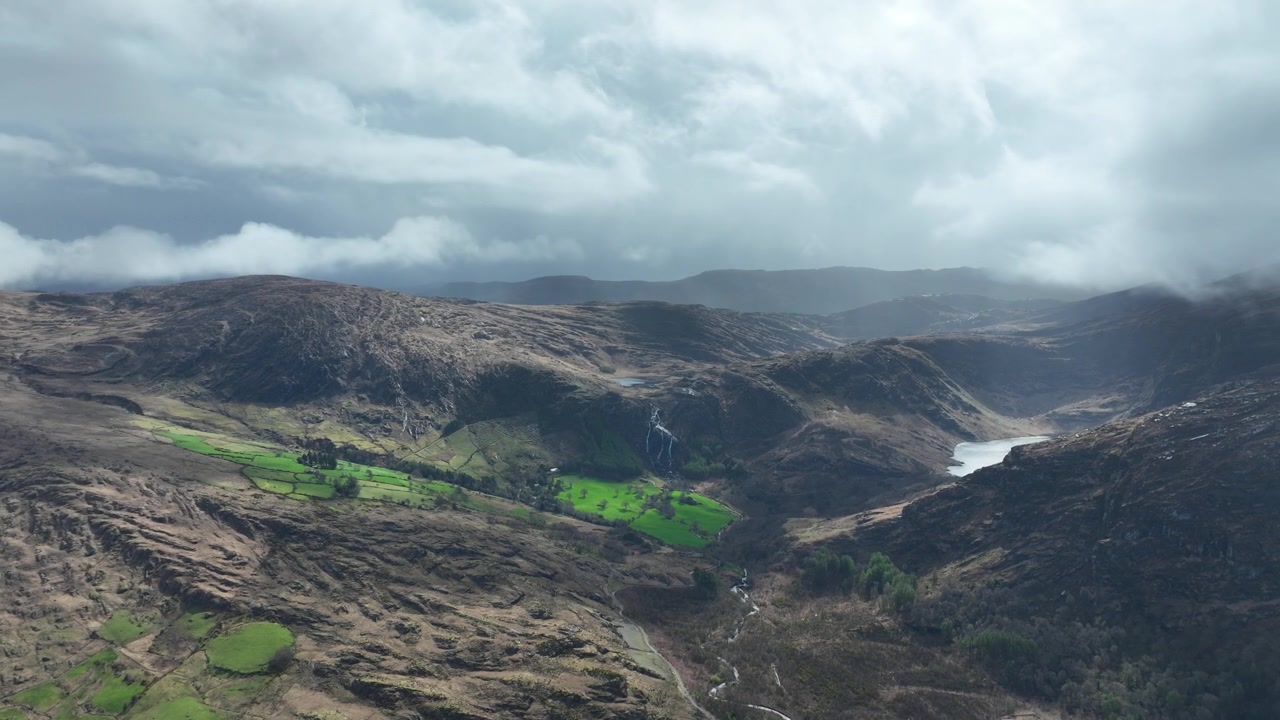 Irlands episke steder: Luftfoto som beveger seg mot venstre over Gleninchquin-dalen, Kerry-fjellene, innsjøer, fossefall og stemningsfulle regnskyer.
