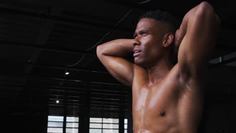 shirtless african american man flexing his muscles in an empty urban building