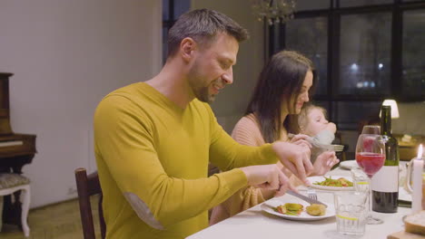 husband and wife talking and eating during a family dinner sitting at table at home