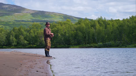 Man-casting-Fishing-line-into-Lake-Inari-in-Lapland,-Northern-Finland-in-summer