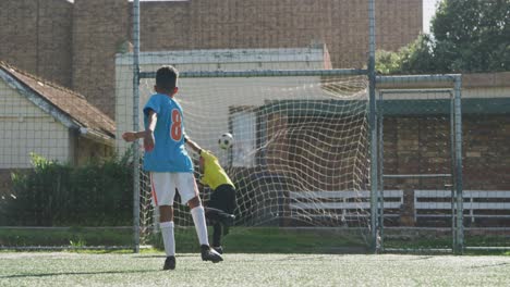 african american soccer kid in blue scoring in a sunny day