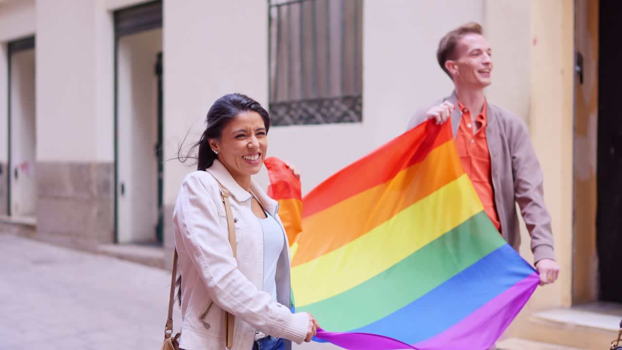 Joyful Man and Woman Waving LGBTQ+ Pride Flag on City Street