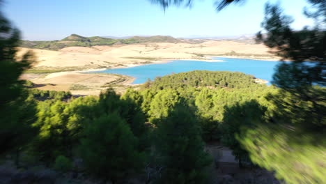 toma interesante volando a través de una pequeña brecha en los árboles para revelar un hermoso paisaje lacustre en un día soleado sin nubes, imágenes arriesgadas de drones