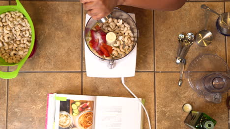 Grinding-black-pepper-over-a-red-pepper-and-cashew-dip-recipe-to-season---overhead-view