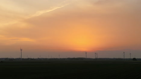 silhouettes of wind turbines at dusk