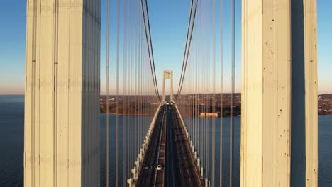 aerial view flying low over traffic on the verrazzano-narrows bridge, golden hour in ny, usa