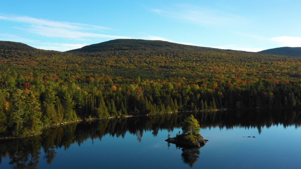 un dron aéreo disparó sobre un tranquilo lago forestal con una pequeña isla y un espeso bosque verde a la distancia del desierto de maine