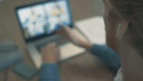 young red haired man having a business video call, working from home with a laptop