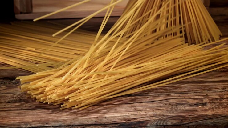 Spaghetti che cadono su un tavolo di legno rustico