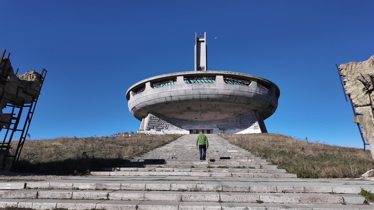 Tourist walking up the stairs to the Buzludzha monument in Bulgaria, a decaying communist era monument