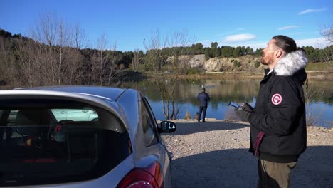 a drone remote pilot takes off the drone from the roof of a car, for a search in a lake